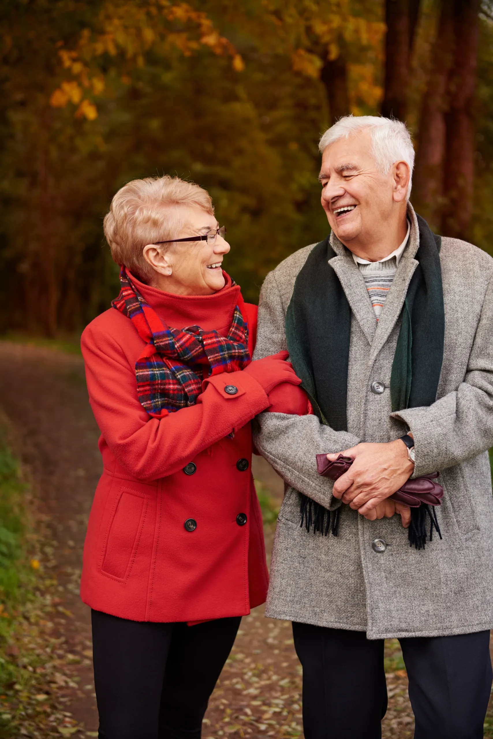 Couple aîné riant ensemble lors d’une promenade en forêt à l’automne